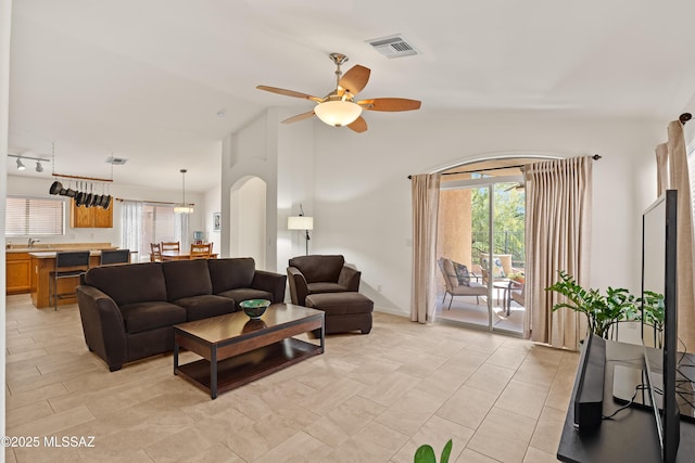 living room with ceiling fan, lofted ceiling, rail lighting, and a wealth of natural light