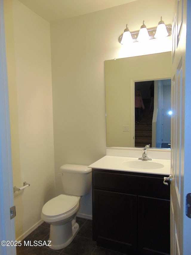 half bathroom with baseboards, vanity, toilet, and tile patterned floors