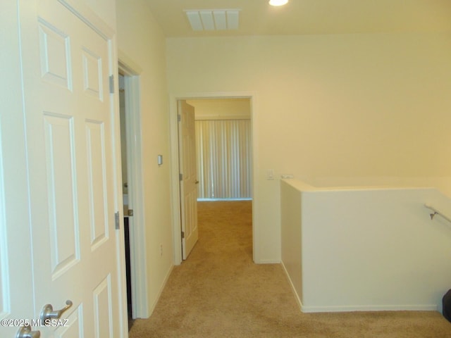 corridor featuring light carpet, baseboards, and visible vents