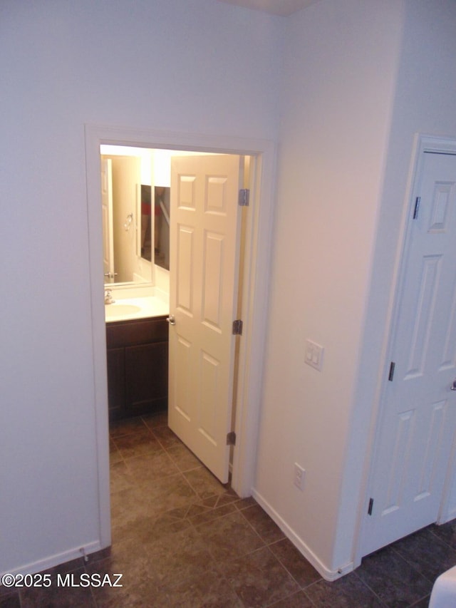 hallway featuring a sink and baseboards