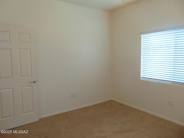 unfurnished room featuring baseboards and light colored carpet