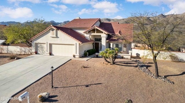 view of front of property featuring an attached garage, a mountain view, a tiled roof, driveway, and stucco siding