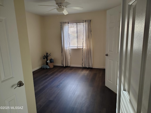 empty room with baseboards, dark wood finished floors, and a ceiling fan