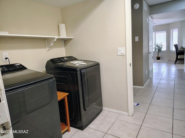 washroom featuring laundry area, baseboards, light tile patterned flooring, and independent washer and dryer