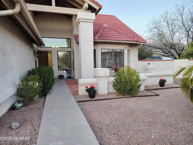 view of exterior entry featuring a tiled roof and stucco siding