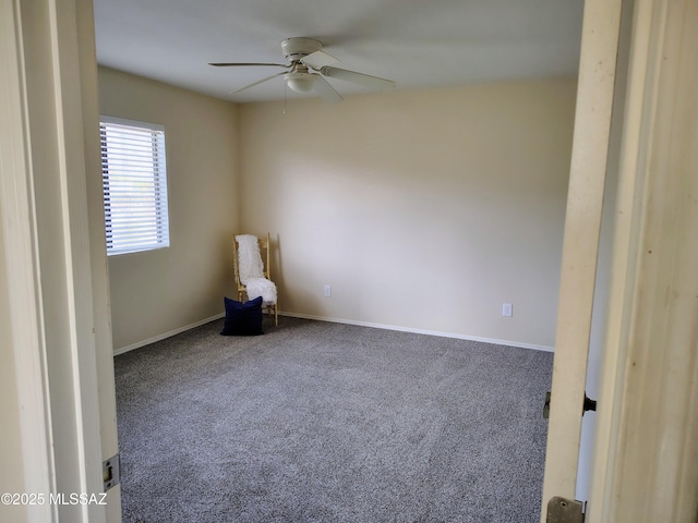 carpeted spare room featuring a ceiling fan and baseboards