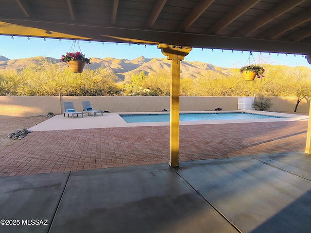 view of pool featuring a fenced in pool, a fenced backyard, a mountain view, and a patio