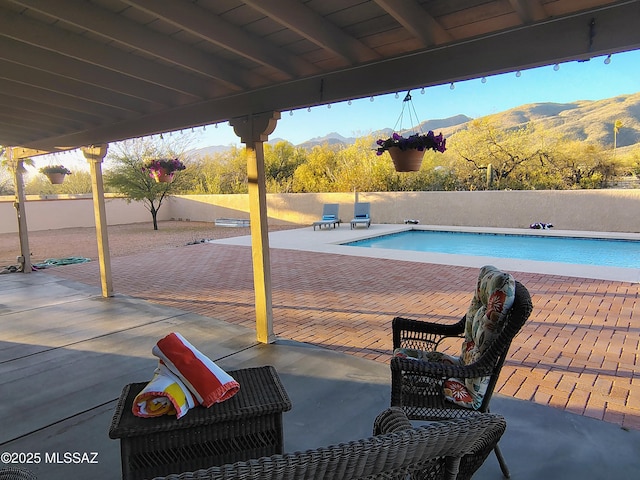 view of pool featuring a fenced in pool, a patio area, a fenced backyard, and a mountain view