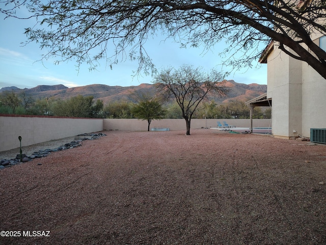 view of yard with cooling unit, a fenced backyard, and a mountain view