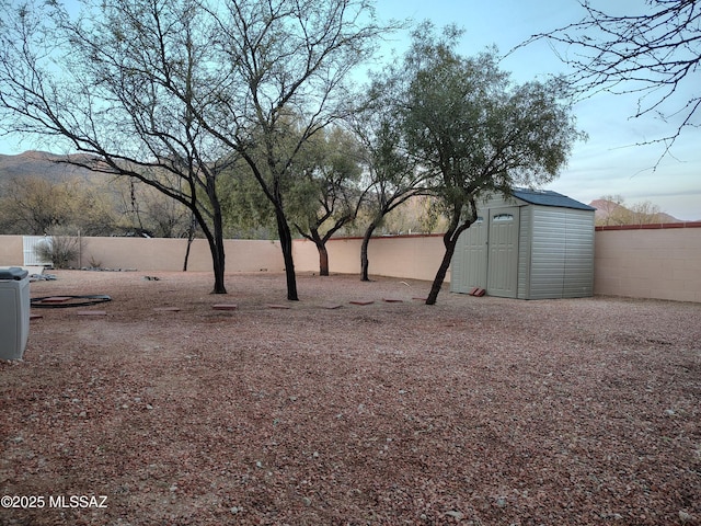 view of yard with a shed, a fenced backyard, and an outbuilding