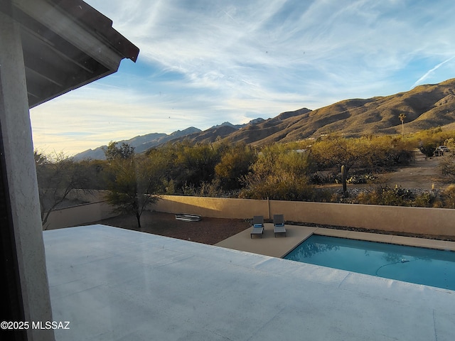 view of swimming pool featuring a patio, a mountain view, and a fenced in pool