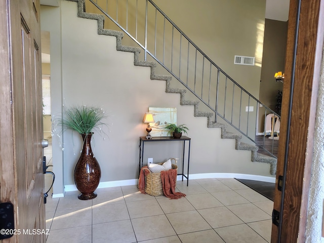 foyer featuring baseboards, stairway, visible vents, and tile patterned floors