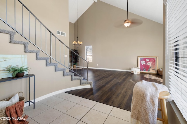 entrance foyer with ceiling fan with notable chandelier, wood finished floors, visible vents, baseboards, and stairs