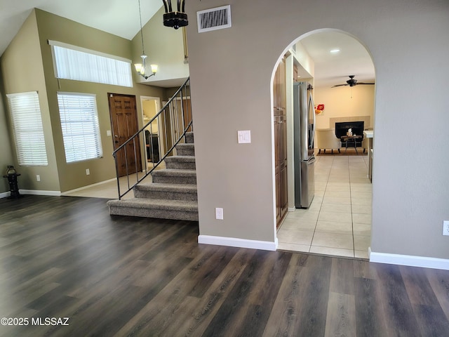 stairway with arched walkways, wood finished floors, visible vents, and a ceiling fan