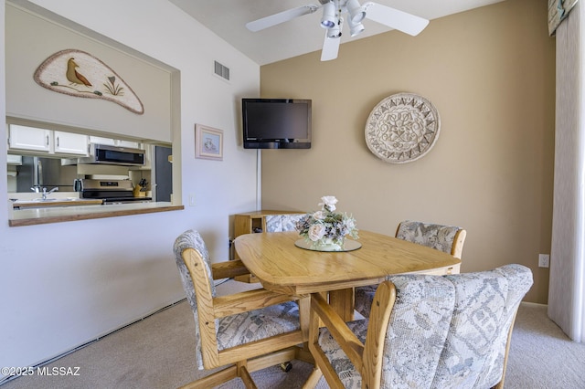 carpeted dining space featuring lofted ceiling and ceiling fan