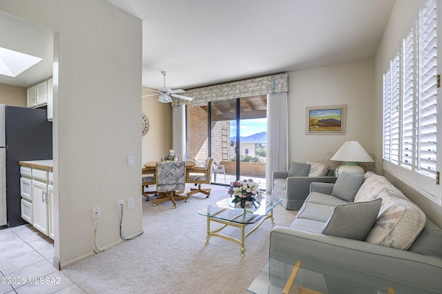 carpeted living room featuring a healthy amount of sunlight, ceiling fan, and a skylight