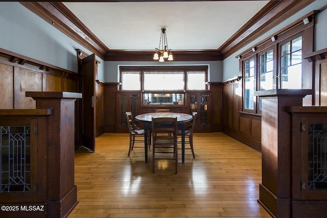 dining room featuring ornamental molding, a healthy amount of sunlight, a tiled fireplace, and light hardwood / wood-style floors