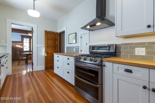 kitchen featuring white cabinetry, wooden counters, pendant lighting, island exhaust hood, and range with two ovens