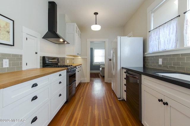 kitchen featuring wall chimney range hood, double oven range, and white cabinets