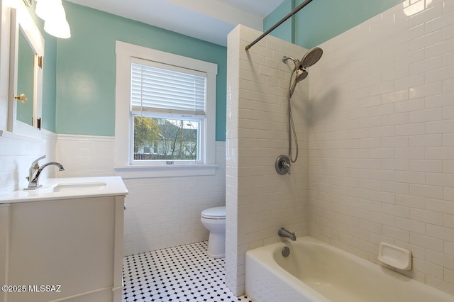 full bathroom with tiled shower / bath, tile walls, tile patterned flooring, vanity, and toilet