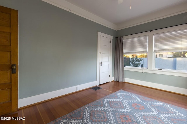 empty room featuring hardwood / wood-style flooring and ornamental molding