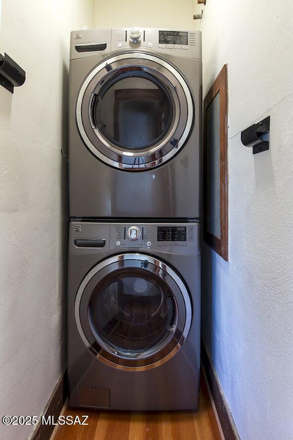 laundry room featuring stacked washer / drying machine and hardwood / wood-style floors