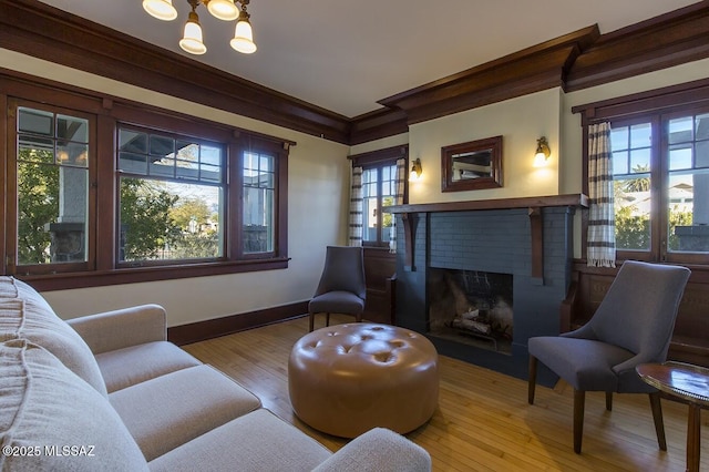 living area featuring a brick fireplace, crown molding, and light hardwood / wood-style floors