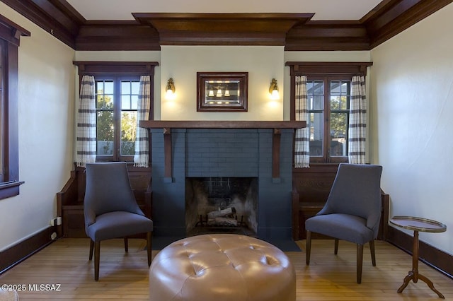 living area with ornamental molding, a brick fireplace, and light hardwood / wood-style flooring