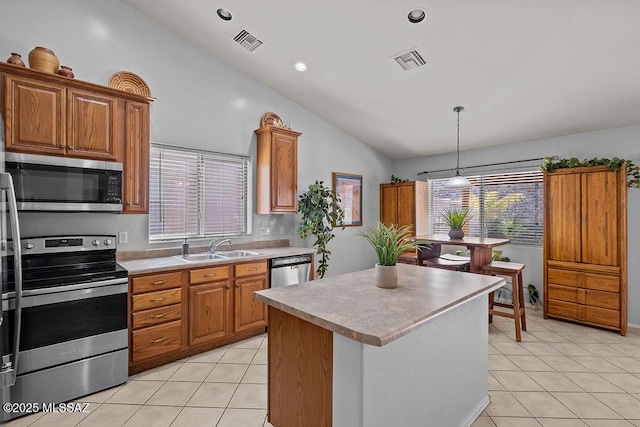kitchen with vaulted ceiling, sink, light tile patterned flooring, a kitchen island, and stainless steel appliances