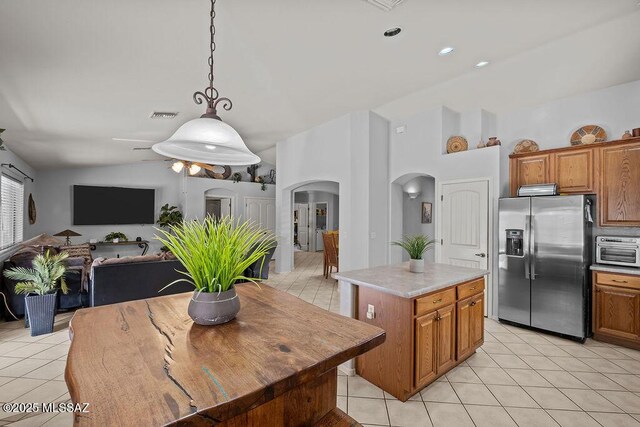 kitchen featuring lofted ceiling, decorative light fixtures, a center island, light tile patterned floors, and stainless steel fridge with ice dispenser