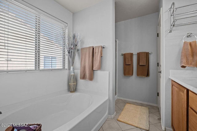 bathroom with a bathing tub, vanity, and tile patterned floors