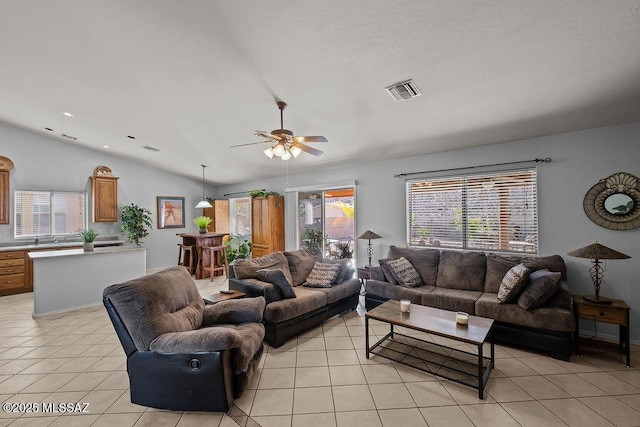 tiled living room featuring ceiling fan, plenty of natural light, and lofted ceiling