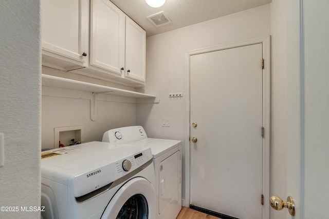 washroom with cabinets, washer and clothes dryer, and light wood-type flooring