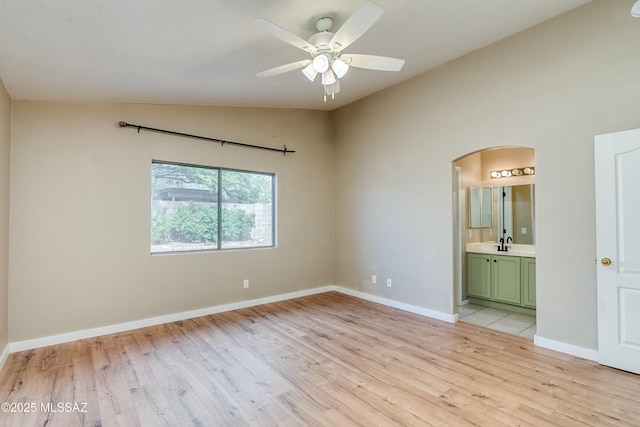 unfurnished room featuring ceiling fan, sink, vaulted ceiling, and light wood-type flooring