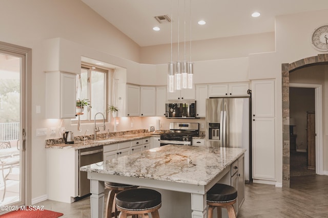 kitchen featuring pendant lighting, a breakfast bar, appliances with stainless steel finishes, white cabinets, and a kitchen island