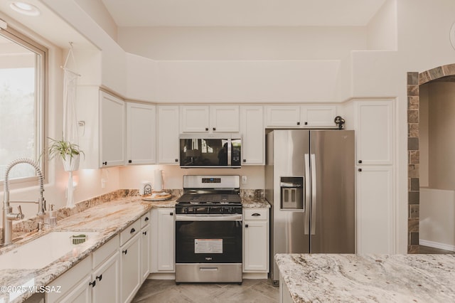 kitchen with light stone counters, sink, stainless steel appliances, and white cabinets