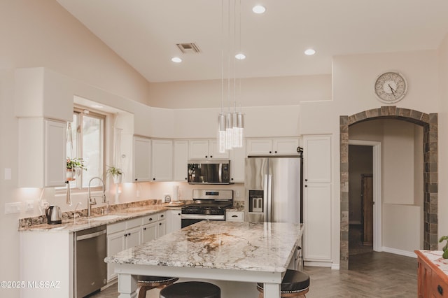 kitchen with white cabinetry, sink, hanging light fixtures, a center island, and stainless steel appliances