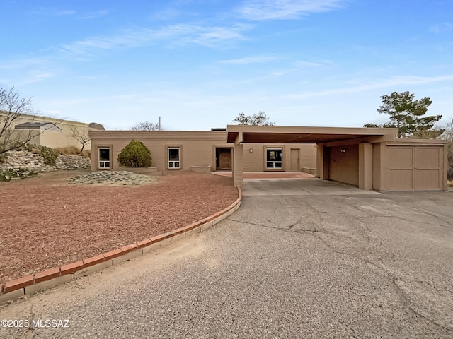 view of front of property featuring a storage shed, aphalt driveway, an outbuilding, and an attached carport