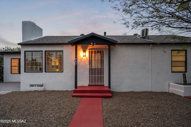 view of front of house with stucco siding and a shingled roof