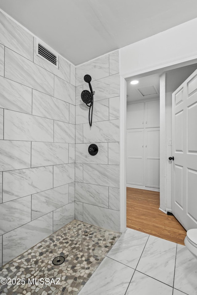 bathroom with toilet and a tile shower