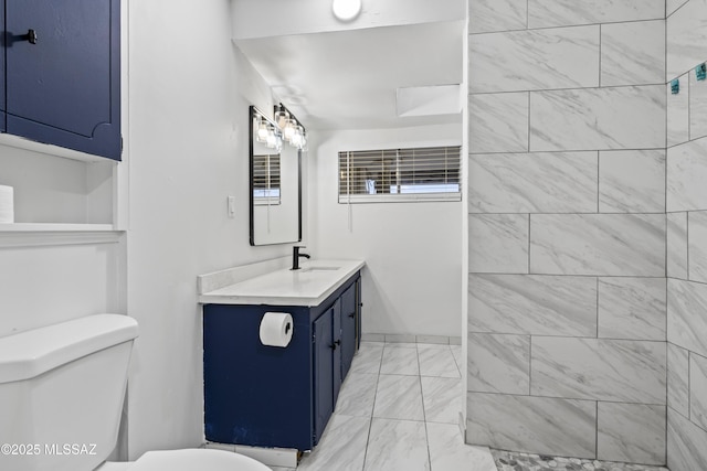 bathroom with toilet, marble finish floor, and vanity