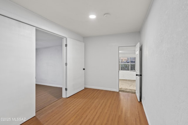 unfurnished room with light wood-style flooring and baseboards