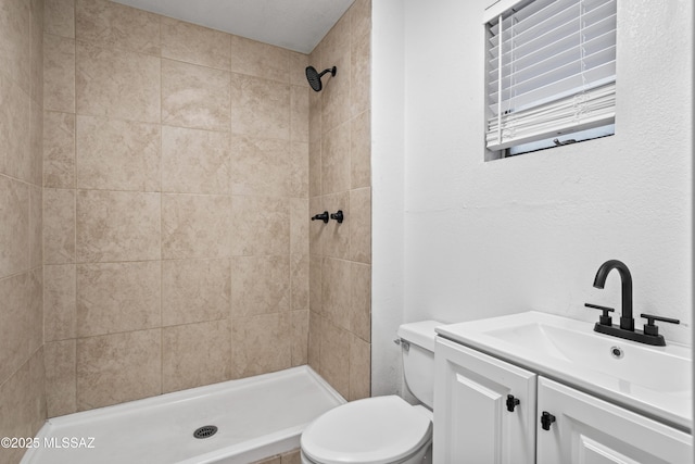 bathroom featuring vanity, tiled shower, and toilet