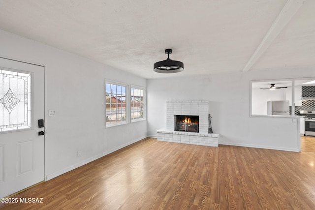 unfurnished living room with ceiling fan, a fireplace, and light hardwood / wood-style flooring