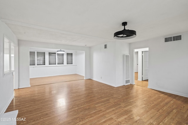 unfurnished room with visible vents, baseboards, and wood finished floors