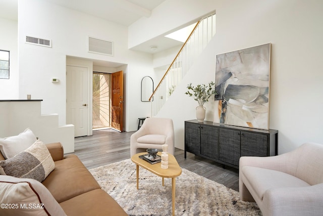 living room featuring wood finished floors, visible vents, and stairs