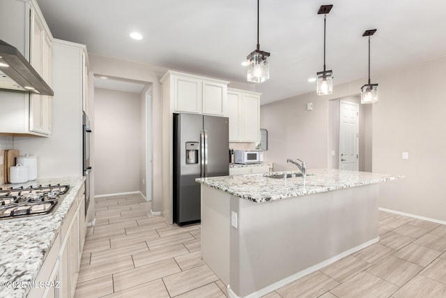 kitchen with appliances with stainless steel finishes, sink, a kitchen island with sink, and wall chimney range hood