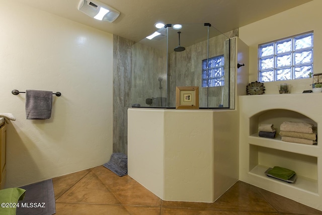 bathroom featuring built in shelves, tile patterned floors, and a tile shower