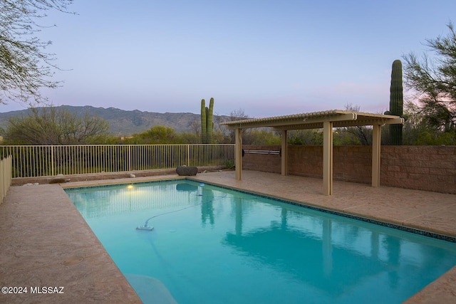 pool at dusk with a mountain view and a patio area