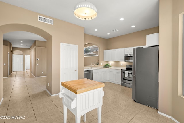 kitchen featuring white cabinetry, sink, light tile patterned floors, and stainless steel appliances